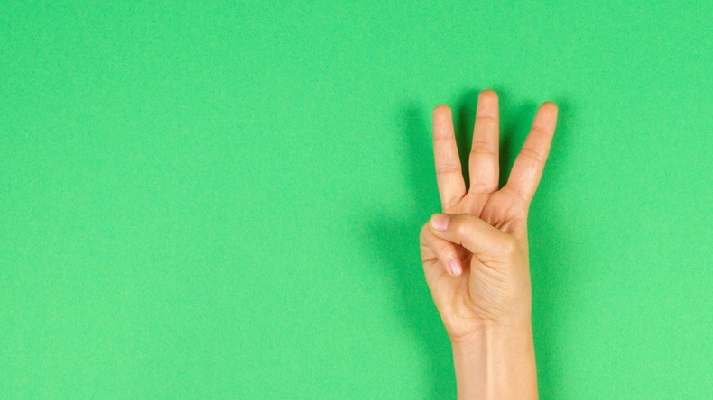 Hand Holding Up Three Fingers On Green Background