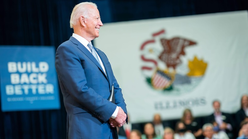 Joe Biden stands in front of a Build Back Better poster