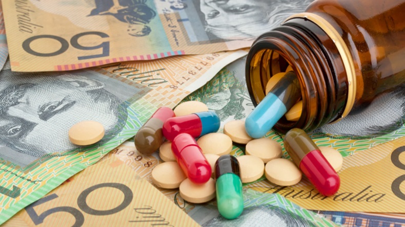 Bottle of pills spilling over pile of Australian dollars