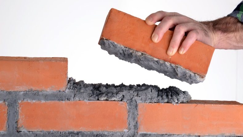 Hand placing brick into wall