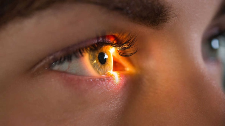 Close-up of woman's eye, with light falling on retina