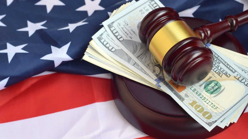 Judge gavel and money on United States of America flag. Many hundred dollar bills under judge malice