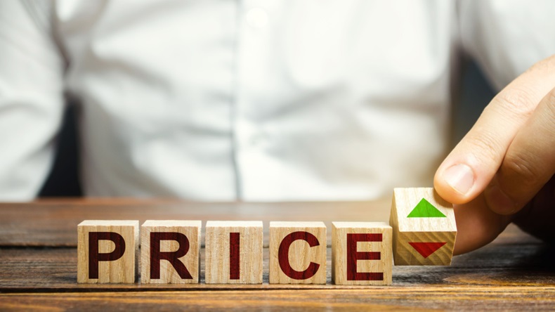 A man changes the position of a block with symbols of growth and decline near the word price