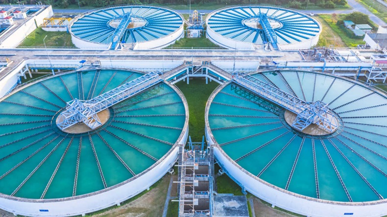 Four wastewater treatment sedimentation pools containing blue-ish liquid, seen from above