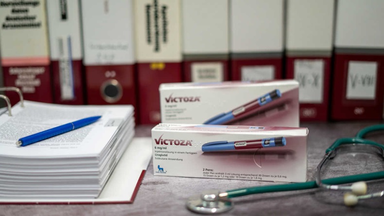 Two boxes of Victoza (liraglutide) on a desk next to stethoscope and open binder folder