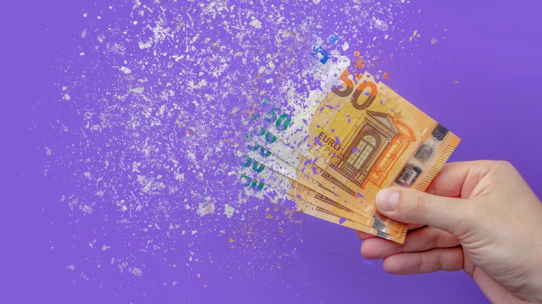 Fifty euro banknotes dissolving in the hand of a man on a purple background
