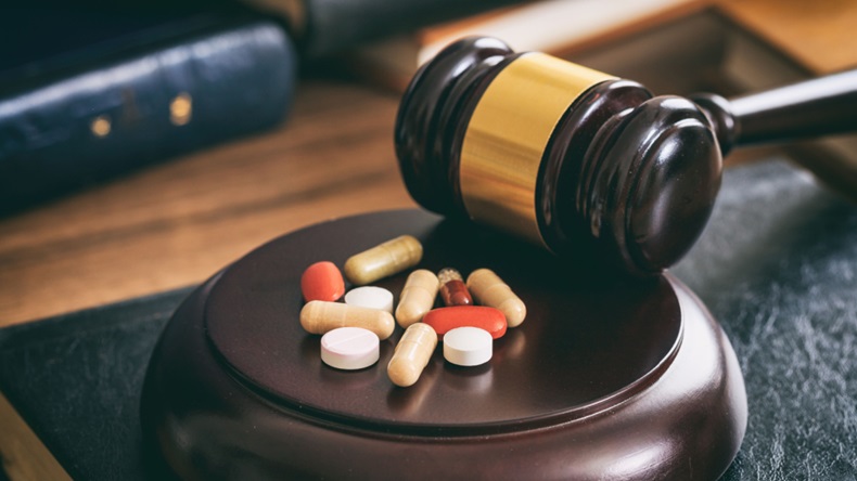 Judge gavel and colorful pills on a wooden desk