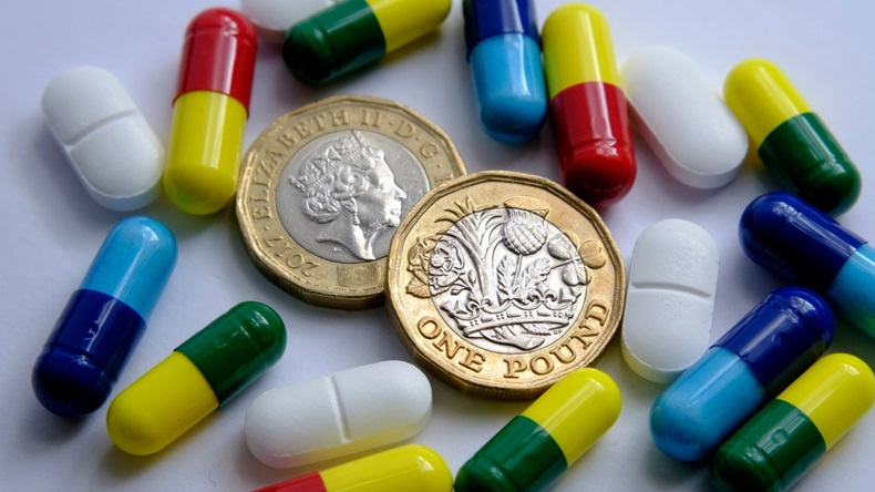 Two pound coins surrounded by tablets and capsules