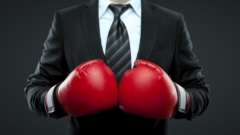 Businessman in suit and tie with red boxing gloves