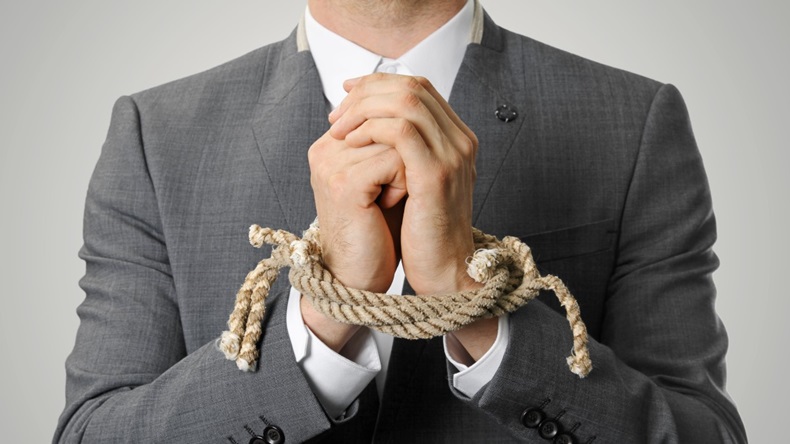 Businessman in suit and shirt with hands tied by rope