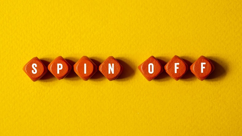 Spinoff spelled out in letters on orange cubes against yellow background