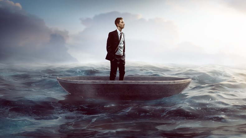 Businessman standing on a small boat in the middle of the sea