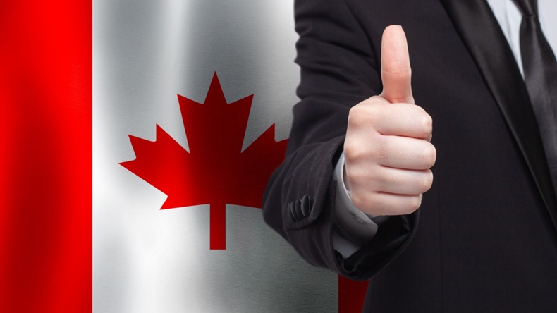 Businessman giving thumbs up in front of Canadian flag