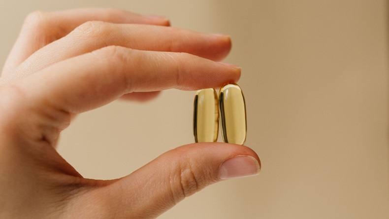 Hand holding up two soft capsule tablets