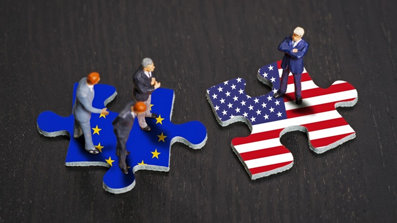 Tiny people standing on jigsaw puzzle pieces with EU and US flags