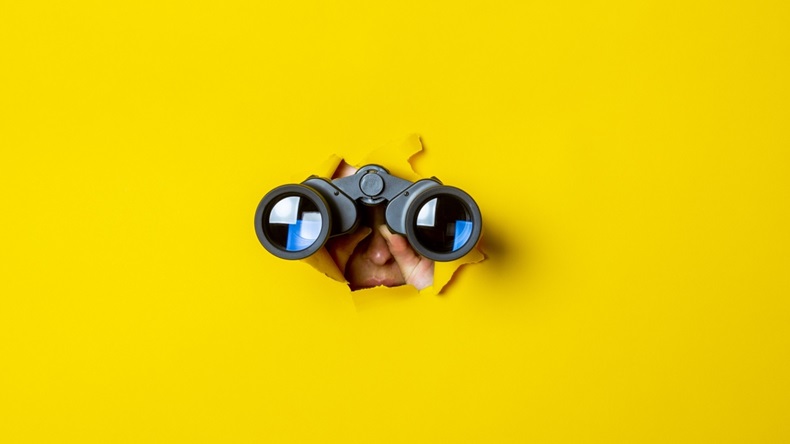 Person looking through binoculars in a yellow background