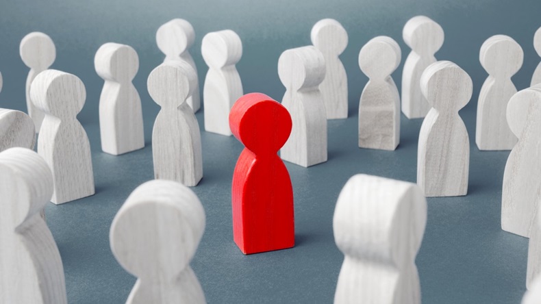 Red wooden figure in crowd of white wooden figures