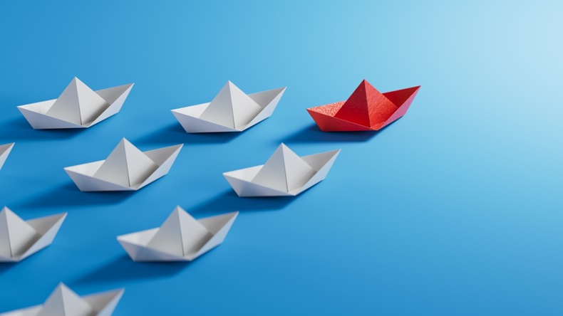 Paper boats on sea, led by red boat