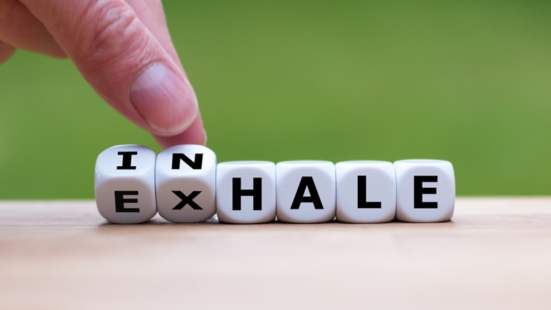 Inhale,Exhale concept. Hand turns dice and changes the word "INHALE" to "EXHALE".